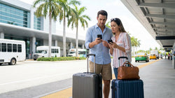 Travelers with suitcases walking past the MIA Mover station toward the Miami car rental center