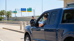 A car hire vehicle approaches an electronic toll gantry on a wide, sunny highway in Texas