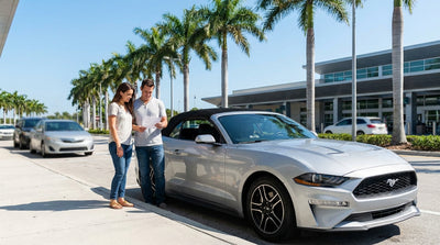 A silver car rental driving along a sunny, palm-lined coastal road in Florida