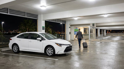 A nighttime view from a car rental driving on a freeway toward the illuminated Los Angeles skyline