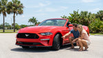 A red convertible car rental parked on a sunny coastal road with palm trees in Florida