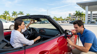 A driver's hands on the steering wheel of a car rental, checking the dashboard controls on a sunny street in Miami