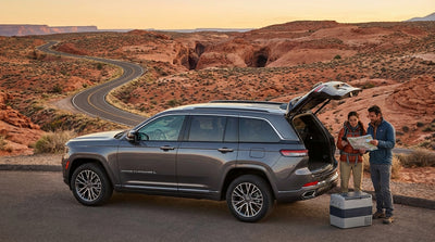 A Las Vegas car hire drives on a highway through the vast desert toward stunning red rock formations