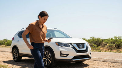 A frustrated driver searches their pockets for keys next to their car hire sedan on a dusty Texas roadside