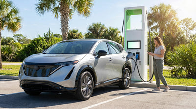 A person charging their electric car rental at a public station with palm trees in sunny Florida