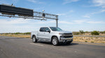 A car rental driving on a sunny Texas highway towards an electronic toll road sign