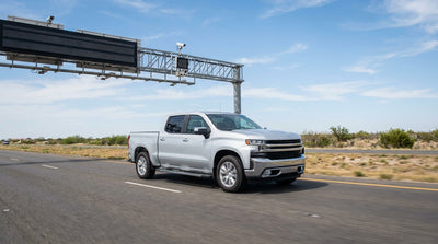 A car rental driving on a sunny Texas highway towards an electronic toll road sign