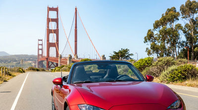 A car hire drives over the Golden Gate Bridge towards the sunny San Francisco skyline