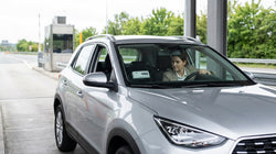 Silver car rental driving through an E-ZPass toll plaza on a Pennsylvania highway