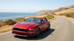 A red car rental driving along a scenic coastal highway in California