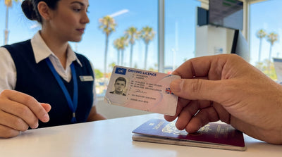 A red convertible car hire driving along a sunny, winding coastal highway in California