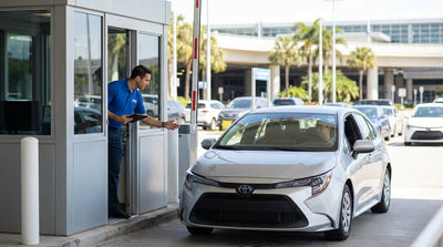 A driver in a modern sedan at the exit booth of a Los Angeles car rental facility