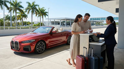 A shiny convertible car rental driving down Ocean Drive in Miami on a bright, sunny day