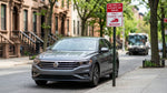 A person parallel parking their car hire on a brownstone-lined street in New York City
