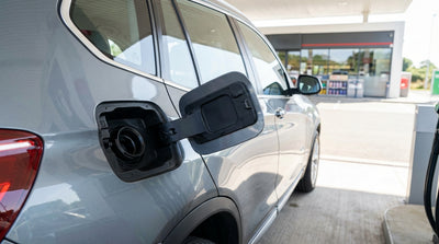 A driver refueling their silver car rental at a modern gas station in sunny California