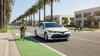 A car rental stopped at a crosswalk for a pedestrian on a sunny street in California