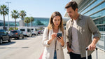 Traveler uses a smartphone in front of the LAX airport terminal before picking up their car rental in Los Angeles