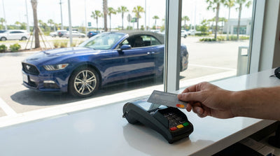 A driver's hand holding a credit card and keys, ready for a car hire journey in the United States