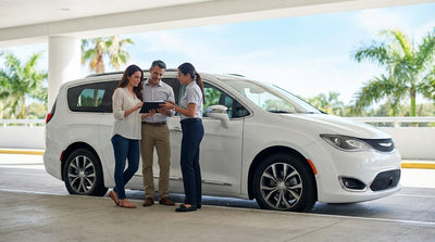 A convertible car hire driving down a sun-drenched coastal road lined with palm trees in Florida