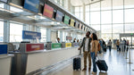 Travelers standing at a shared car rental desk with multiple brand signs in San Francisco airport