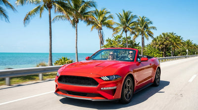 A white convertible car rental driving the scenic Overseas Highway in the Florida Keys on a sunny day