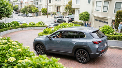 A car rental navigates the tight, flower-lined turns of the famous crooked Lombard Street in San Francisco