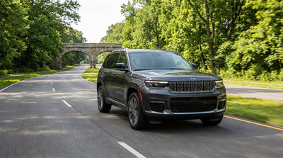 A modern car rental SUV driving along a scenic, tree-lined New York parkway in autumn