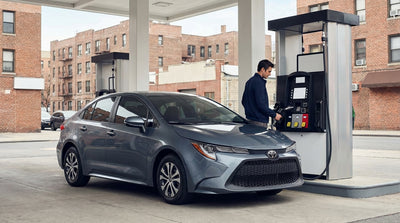 A driver refuels their car hire at a gas pump with the impressive New York City skyline visible in the background