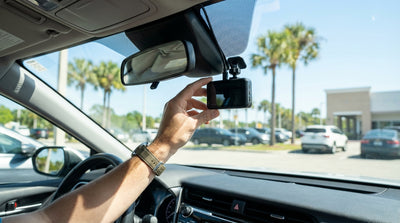 View from the driver's seat of a car rental in Orlando, with a dash cam filming a sunny palm tree-lined road