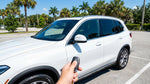 White car rental driving on a sunny coastal highway lined with palm trees in Florida