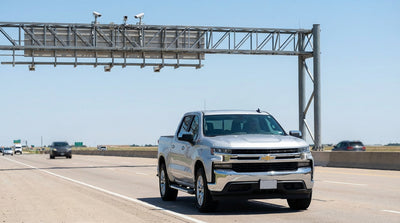 A silver car hire drives down a wide, sunny highway in Texas, with other cars and open landscape visible
