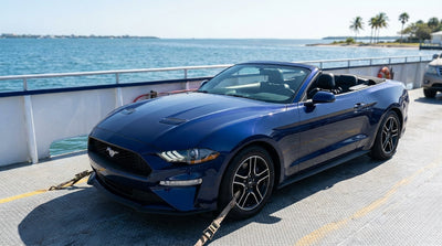 A white car hire vehicle parked on a ferry deck with the sunny Florida coastline in the background