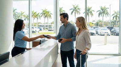 A person drives a convertible car hire down a sun-drenched street lined with palm trees in Miami