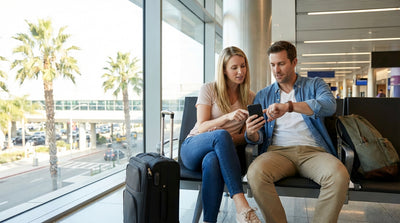 Traveler with a suitcase waits by a row of cars at a sunny car rental agency in Los Angeles
