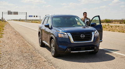 A car hire vehicle with its hood up on the shoulder of a wide Texas toll road under a sunny sky