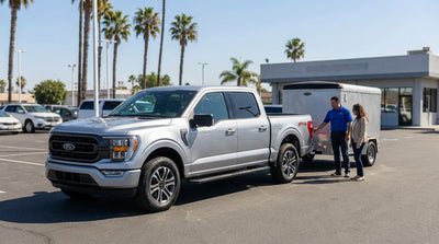 A car rental SUV towing a small trailer on a scenic highway with California's golden hills in the background