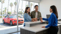 Close-up of a person handing a credit card to an agent at a car rental desk in Los Angeles