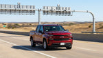 White car rental passing under an electronic toll gantry on a Texas highway