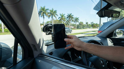 Driver's view from a Florida car hire with a phone in a windscreen mount overlooking a sunny, palm-lined road