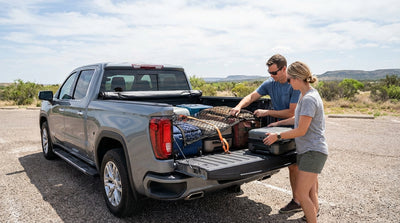A person loads luggage into the bed of a pick-up truck car hire on a dusty road in Texas