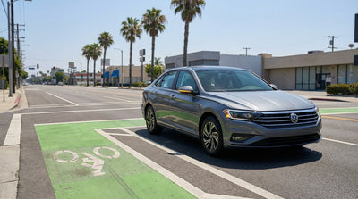 A car hire turning right across a green bike lane on a sunny street in California