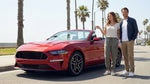 Person driving a convertible car rental along a sunny coastal highway in California overlooking the ocean