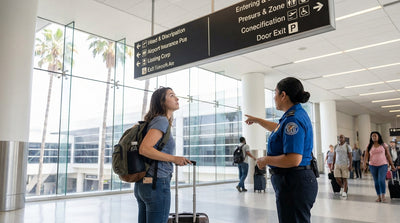 A purple car rental shuttle waits for travelers with luggage outside a sunny Los Angeles airport terminal