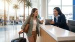 A person stands at a busy car hire desk at the airport in Orlando discussing their reservation