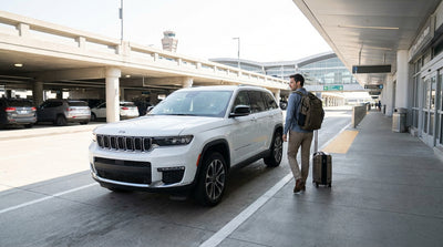 A car hire drives over the Brooklyn Bridge with the New York City skyline in the background at sunset