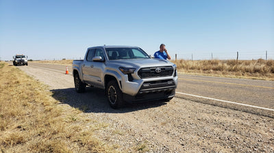 Tow truck loading a broken down car rental on a rural highway in Texas