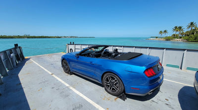 A car hire parked on the open deck of a ferry boat sailing under a clear blue sky in Florida