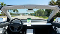 Smartphone displaying a navigation map on the dashboard of a car rental parked on a sunny Florida street