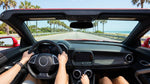Driver behind the steering wheel of a car rental cruising down a sunny highway in Florida