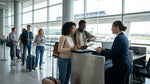A brightly lit car hire counter inside New York's JFK airport terminal with a customer waiting